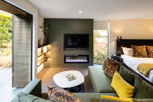 a bedroom with a bed and a living room with a fireplace at Queenstown Park Boutique Hotel in Queenstown