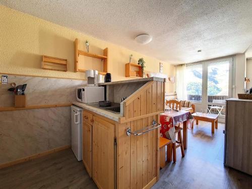 - une cuisine avec des placards en bois et une table dans une pièce dans l'établissement Résidence Villaret - Studio atypique avec beaucoup de rangement MAE-2694, aux Menuires