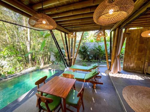 un patio con tavolo e sedie accanto alla piscina di Eco Bamboo Island Bali - Bamboo House #2 a Selat