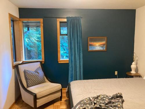 a bedroom with a bed and a chair and a window at Hidden Creek Hideaway in Roberts Creek