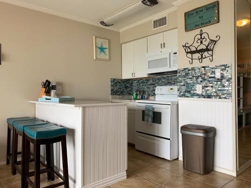 a kitchen with a counter and some stools in it at Corpus Christi North Beach Cozy Condo, 2 Heated pools and Balcony Ocean Views! in Corpus Christi