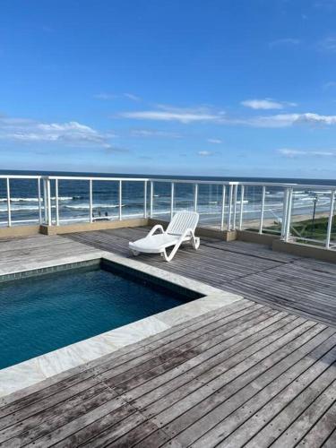 a deck with a chair and a swimming pool on the beach at Apartamento pé na areia in Matinhos