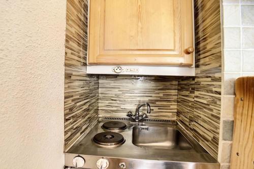 une cuisine avec un évier et des armoires en bois dans l'établissement Résidence Dorons - Studio lumineux · Centre station · Balcon MAE-3414, aux Menuires