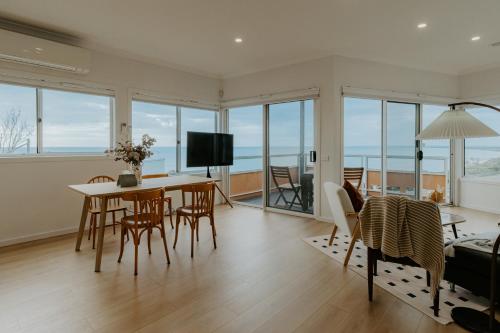 a living room with a table and chairs and a television at Pudding's Home Luxury Oceanfront Escape in Frankston