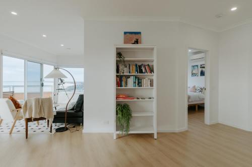 a living room with a book shelf with books at Pudding's Home Luxury Oceanfront Escape in Frankston