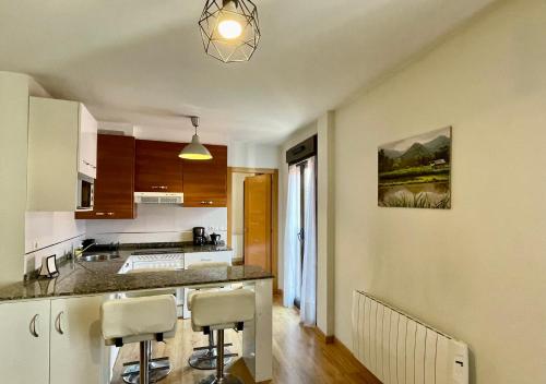 希洪Apartamento casco histórico Gijón的厨房配有柜台和2个酒吧凳