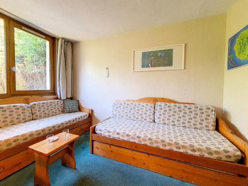 une petite chambre avec deux lits et une table dans l'établissement Résidence Boedette A - Studio classique · Départ et retour skis aux pieds MAE-3564, aux Menuires