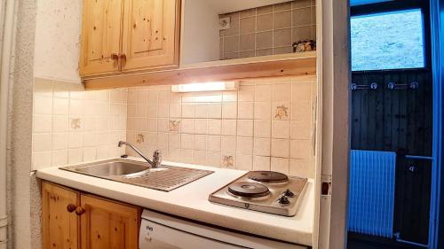 une petite cuisine avec un évier et une cuisinière dans l'établissement Résidence Aravis - Appartement spacieux · Départ et retour ski aux pieds · Balcon vue montagnes MAE-3704, aux Menuires