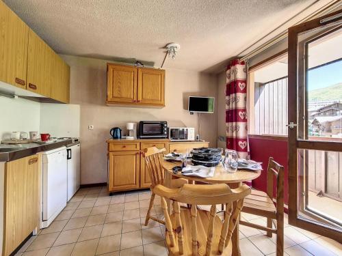 une cuisine avec une table et des chaises et une cuisine avec une fenêtre dans l'établissement Résidence Sarvan - Appartement · Balcon · Quartier Preyrand · Pied des pistes MAE-4594, aux Menuires