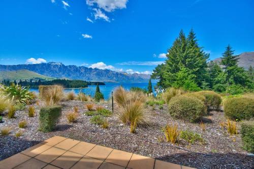a garden with plants and a lake in the background at Lakeview Apartment in Queenstown