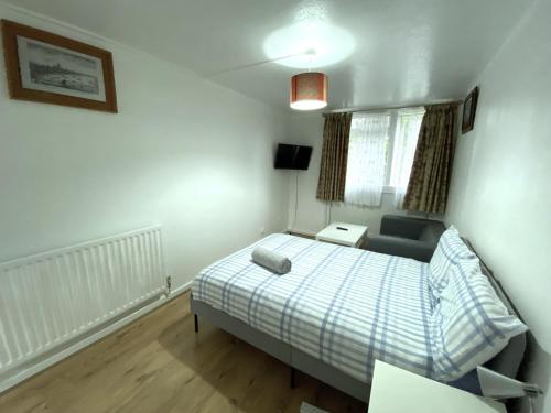 a small bedroom with a bed and a chair at Laret Guest House in London