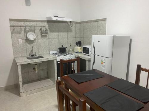 una pequeña cocina con nevera blanca y mesa en Departamentos Ohana, en San Ramón de la Nueva Orán