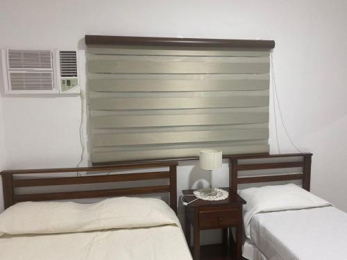 Un dormitorio con 2 camas y una ventana con un ciego en Departamentos Ohana, en San Ramón de la Nueva Orán