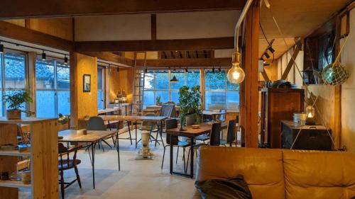 un restaurante con mesas, sillas y ventanas en コワーキングスペース kuzume Base ゲストハウス 古朴-MOKU-1棟貸の宿, en Konan