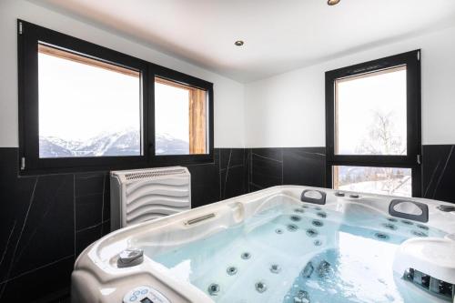 La salle de bains est pourvue d'une baignoire et de 2 fenêtres. dans l'établissement Résidence OrÉe Du Bois - APPARTEMENT N°6 L'OREE DU BOIS MAE-9671, à Montvalezan