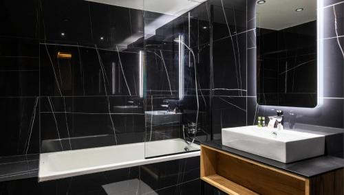 une salle de bain carrelée noire avec un lavabo et un miroir dans l'établissement Résidence OrÉe Du Bois - APPARTEMENT N°2 L'OREE DU BOIS MAE-9721, à Montvalezan