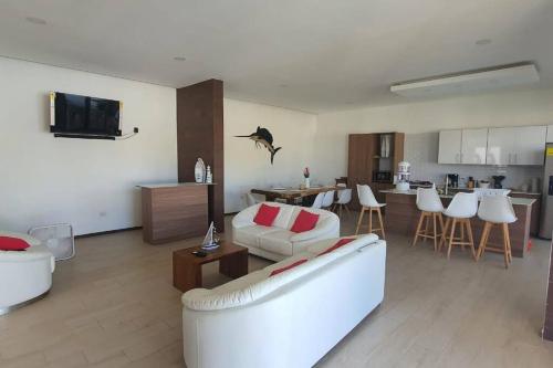 a living room with a white couch and a kitchen at Casa Vacacional Almendros in El Conacaste