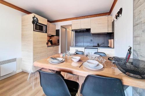 une cuisine avec une table en bois et quelques chaises dans l'établissement Résidence Valmonts A - Appartement agréable · Balcon sud · Pied des pistes MAE-6511, aux Bruyères