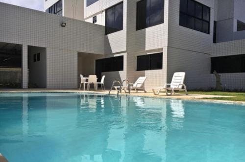 a swimming pool with chairs and a building at Recife Olinda perto de tudo in Recife