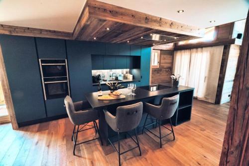 une cuisine avec une île noire entourée de chaises dans l'établissement Chalet Nyumbani - Exceptionnel : Chalet prestigieux, belles finitions, proche pistes de ski MAE-2361, aux Gets