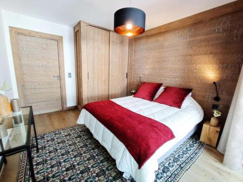 une chambre avec un grand lit avec des oreillers rouges dans l'établissement Résidence Le Vieux ChÊne - Appartement avec double balcon au coeur du village MAE-2411, aux Gets