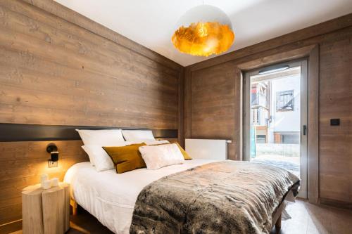 une chambre avec un grand lit avec un mur en bois dans l'établissement Résidence Le Vieux ChÊne - Appartement chic 