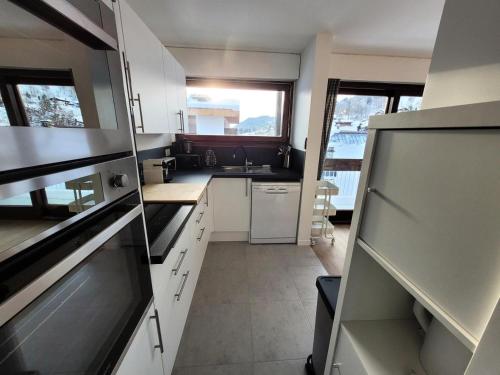 une cuisine avec des placards blancs et une grande fenêtre dans l'établissement Résidence Le Vorzay - Appartement Cosy 4 Ambiance 