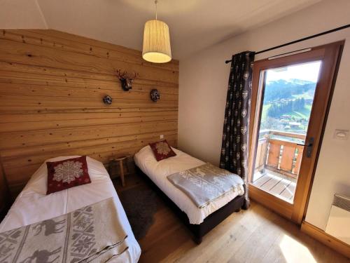 une chambre avec deux lits et une fenêtre dans l'établissement Chalets Chantemerle - Chalet en surplomb du village, idéal pour famille MAE-2541, aux Gets