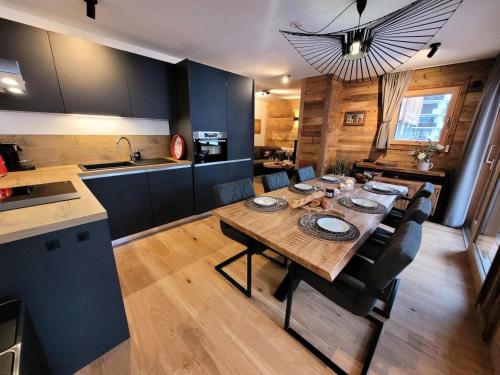 une cuisine et une salle à manger avec une table et des chaises en bois dans l'établissement Résidence Essentiel - Appartement de standing, esprit cosy, large terrasse MAE-2531, aux Gets