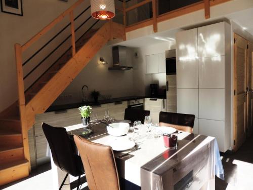 - une cuisine avec une table à manger, des chaises et un escalier dans l'établissement Les Chalets Carline - Appartement T3, vue dominante sur les pistes MAE-2561, aux Gets