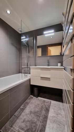 une salle de bain avec un lavabo et un grand miroir dans l'établissement Résidence Le Stella - Appartement de standing au cœur du village MAE-2571, aux Gets