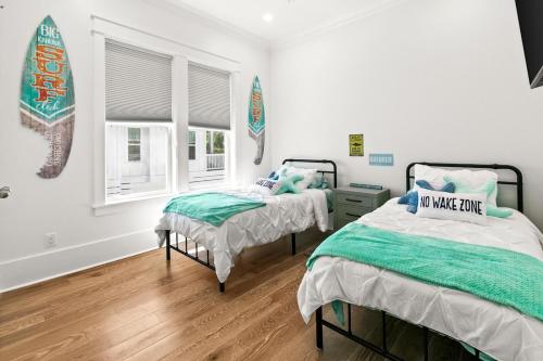 1 dormitorio con 2 camas y una tabla de surf en la pared en Barefoot Bayou, en Santa Rosa Beach