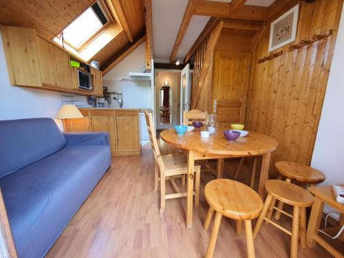un salon avec une table et un canapé bleu dans l'établissement Résidence Mas Du Peyron - Appartement lumineux · Accès piste par navette · Casier à skis privatif MAE-8394, à Saint-Chaffrey