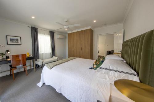 a bedroom with a large white bed and a desk at Heal House in Brisbane