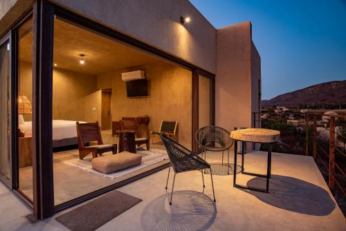 a room with a balcony with a bed and a table and chairs at Mexico en la Piel in Valle de Guadalupe