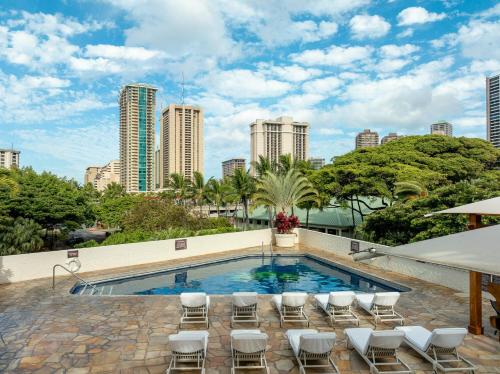 a swimming pool with chairs and a city skyline at Private owned studio at Luana Hotel, partial ocean & city view, and no resort or extra fees!!! in Honolulu