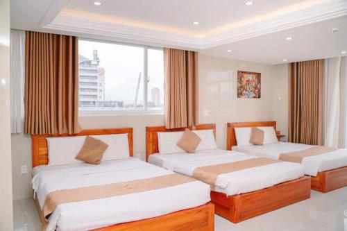 a bedroom with two beds and a large window at Dragon Hotel & Apartments Đà Nẵng in Da Nang