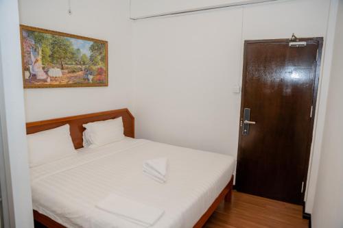 a small bedroom with a bed and a door at Ong Hotel in Tawau