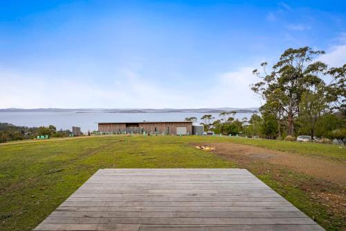a large grassy field with a building in the background at The Outlook on Mount Louis - Stunning Views in Tinderbox