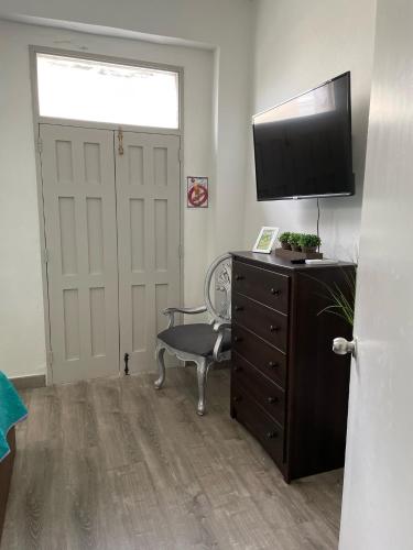 a room with a dresser with a television and a chair at 310Guest-House La Vida in San Juan