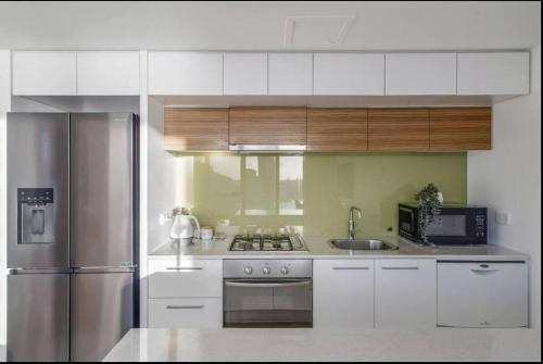 a kitchen with white cabinets and a stainless steel refrigerator at Breathtaking Harbour Views in Melbourne