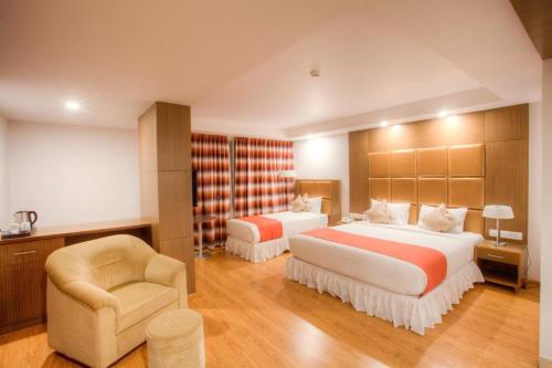 a hotel room with two beds and a chair at The Atrium Boutique Hotel in Mysore