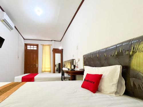 a bedroom with two beds and a desk at RedDoorz Syariah Near Alun-Alun Tulungagung in Tulungagung