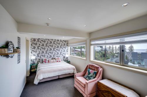 a bedroom with a bed and a pink chair at Seabreeze Penthouse - Napier Holiday Apartment in Napier