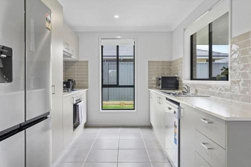 una cucina con armadietti bianchi e una finestra di Time Out Beautifully decorated new home a Cessnock