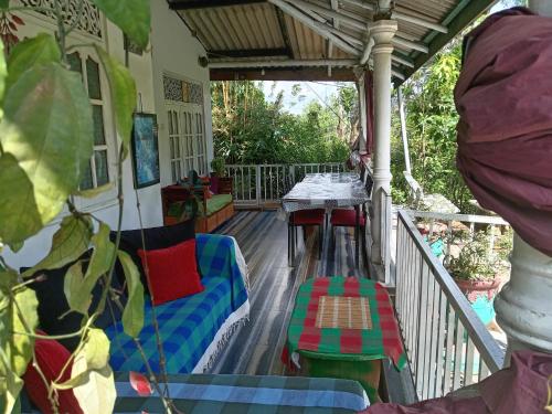 a porch with a swing and a table and chairs at Tunnel Gap Homestay in Ella