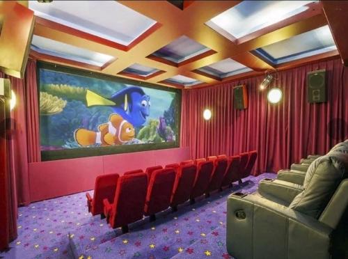 a movie room with a large screen with red chairs at Entire Maggie's Guesthouse - free cinema, pool, spa, tennis court, karaoke, more! in Warrandyte