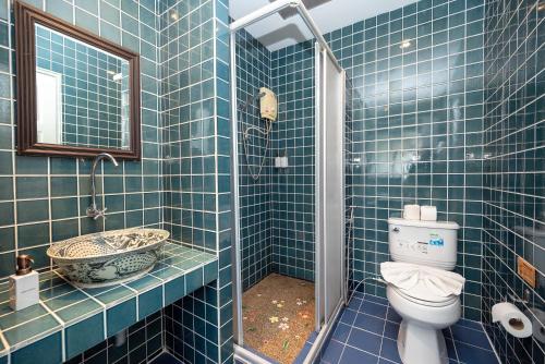 a blue tiled bathroom with a toilet and a sink at Le Charme Sukhothai Historical Park in Sukhothai