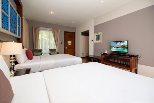 a hotel room with two beds and a flat screen tv at Le Charme Sukhothai Historical Park in Sukhothai