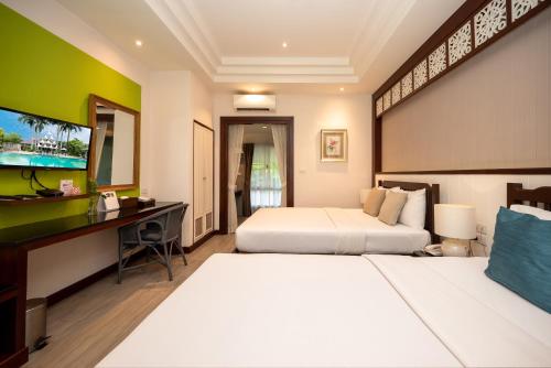 a hotel room with two beds and a desk at Le Charme Sukhothai Historical Park in Sukhothai